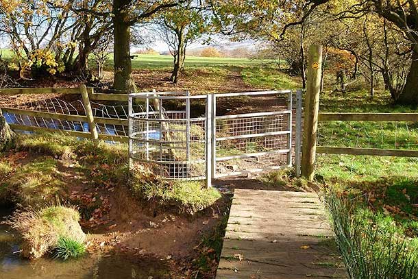 New metal gate installation next to a pond.