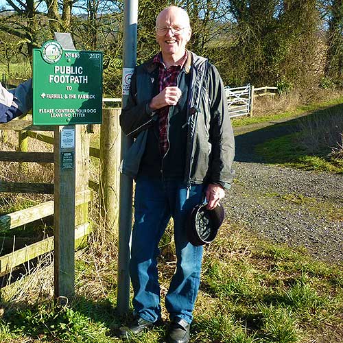 An area officer next to a sign, smiling