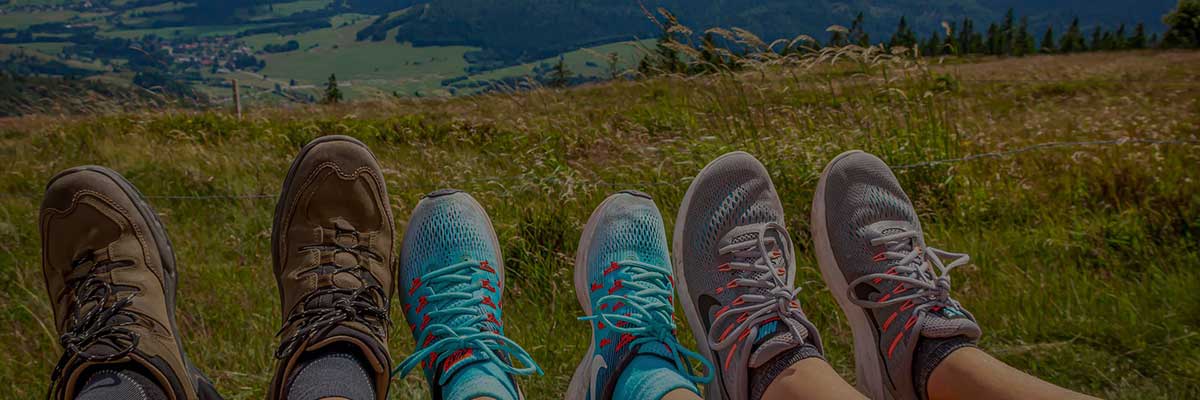 Three people's feet, with hills in the background