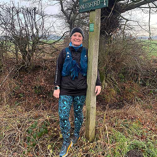 A path checker next to a sign, smiling